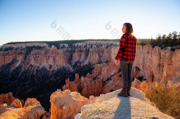 在阳光明媚的日落中欣赏美国风景的美丽景色的妇女。拍摄于美利坚合众国犹他州布莱斯峡谷国家公园.