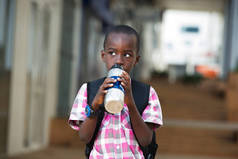 小小学生背着背包, 在下课的路上, 站在瓶子里喝水.