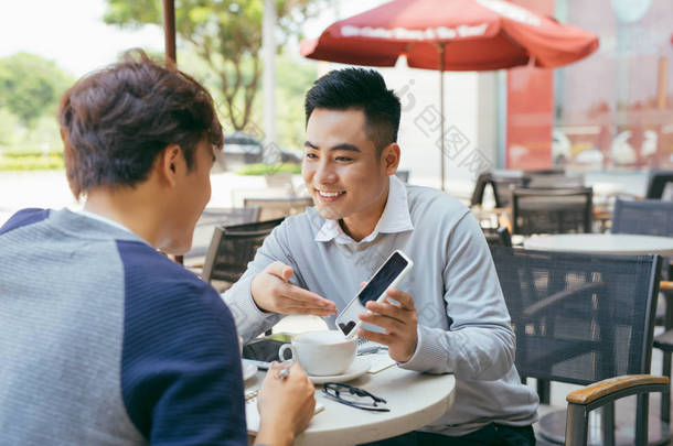 正在检查库存。在当地咖啡馆的一次会议上, 两个在笔记本电脑上工作的商业伙伴高兴地微笑着--形象