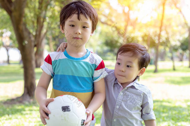 英俊的哥哥拿着球, 准备和弟弟在公园里玩。小男孩总是和他的大哥在一起, 他们总是在一起玩。他们彼此相爱