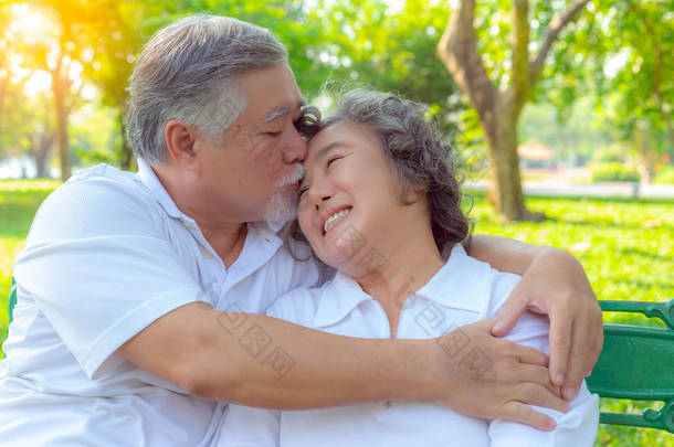 肖像画浪漫的老夫妇。有吸引力的英俊的老丈夫拥抱和亲吻他的老妻子与爱。爷爷奶奶相爱很久了。他们是浪漫的一对