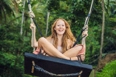 在热带巴厘岛热带雨林中荡秋千的年轻旅游妇女