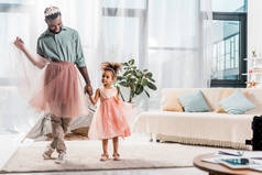快乐的非洲裔美国父亲在可爱的粉红色 tutu 和可爱的女儿在美丽的礼服 