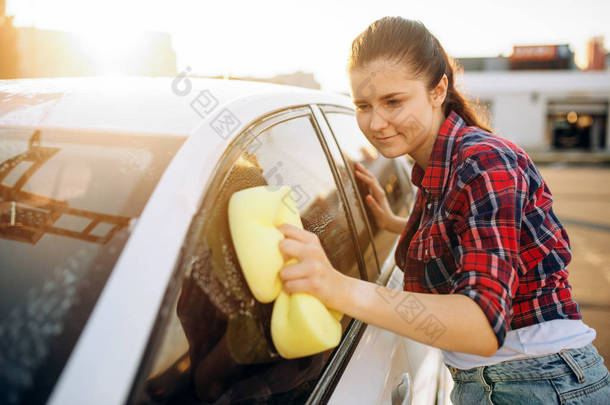 年轻女子用海绵擦洗车玻璃用泡沫, 洗车。女士在自助洗车。户外洗车
