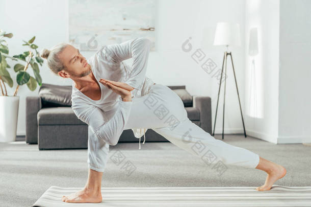 男子站在旋转的侧角锻炼, 帕里夫特塔帕斯瓦科纳萨纳在瑜伽垫在家里的瑜伽垫