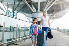 带着行李在机场的年轻母亲和女儿