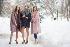 三件毛皮大衣的时装模特。全长肖像的年轻美丽优雅的妇女穿着毛皮大衣。时尚女孩在街上散步冬天.