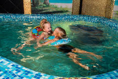 两个好孩子在蓝水池游泳。男孩和女孩有乐趣在水室内