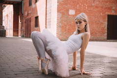 美丽的优雅芭蕾舞女演员看着相机, 而在街上跳舞 