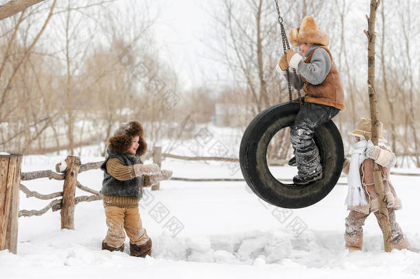 三年幼的孩子在<strong>车</strong>轮上玩耍和<strong>摇摆</strong>, 挂在房子的后院, 一个温暖的冬天天