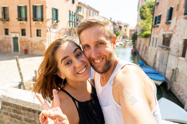 愉快的夫妇自拍与智能手机在威尼斯的运河著名的欧洲城市在意大利夏季假期旅游环游欧洲度假爱和蜜月概念.
