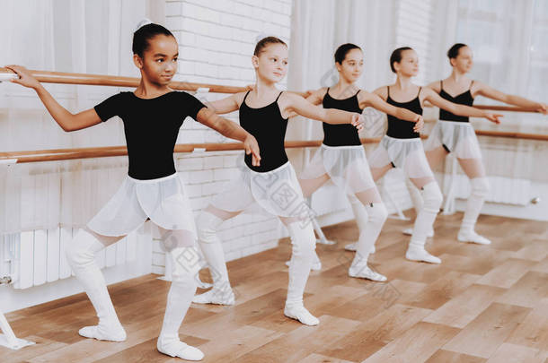 室内年轻女孩团体的芭蕾培训。古典芭蕾。巴莱丽娜·图图的女孩。室内训练。可爱的舞者大厅里的表演。舞蹈练习。穿白色衣服的女孩.