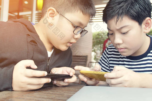 愉快的亚洲男孩<strong>玩手机</strong>游戏在线智能<strong>手机</strong>在一起。男孩和朋友与战略有乐趣.