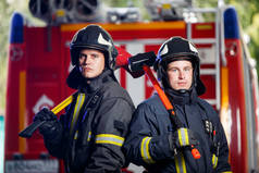 两名消防员拍照, 手里拿着斧头在消防车旁边