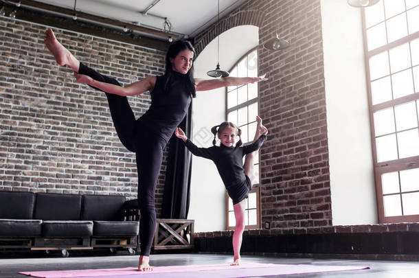 母亲和小女儿做站立分开的<strong>腿</strong>舒展锻炼保持平衡