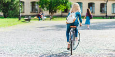 后视图的学生背包骑自行车在街上