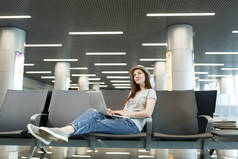 年轻的思考旅行者的旅游妇女在笔记本电脑上, 查找, 等待在大堂大厅在国际机场。周末出游的旅客出国旅行。航空旅行, 飞行旅途概念