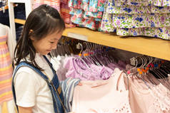 快乐的亚洲女孩选择服装商场或服装店, 销售和消费观念的概念