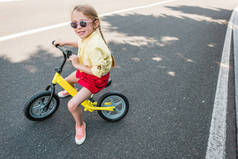 高角度看可爱的微笑的孩子在太阳镜骑自行车