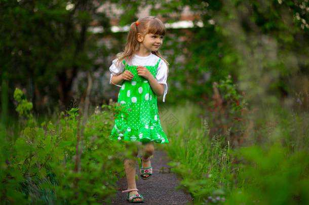 小女孩在阳光明媚的夏<strong>日漫</strong>步在绿色花园里