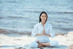有吸引力的亚洲妇女沉思在安贾莉手印 (称呼封印) 在瑜伽垫上的海上姿势 