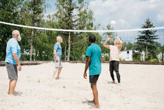 多文化的老朋友夏天在沙滩上打排球