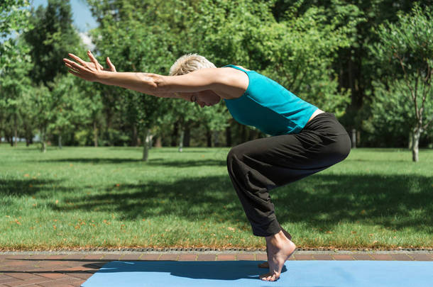 妇女在公园<strong>瑜伽垫</strong>上练习<strong>瑜伽</strong>的侧面视图