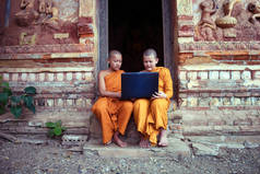用膝上型计算机学习与朋友坐在潘文凯的佛教教会中的新手僧佛教教育.