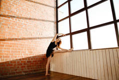 优雅的芭蕾舞演员在一个黑色的包舞蹈室在风格的阁楼与大窗户
