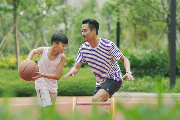 中国父子早晨在花园里打篮球