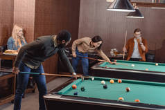 年轻成功的多元朋友在酒吧玩台球