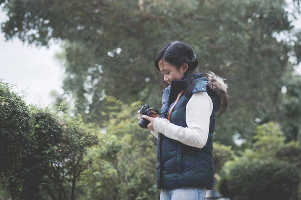 美丽的亚洲女孩在温暖的衣服与<strong>复古</strong>相机<strong>拍摄</strong>在公园的照片