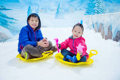 男孩和女孩乘坐雪橇在冰在室内雪土地