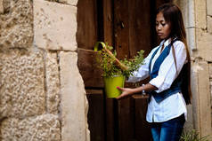美丽的年轻女子挂在木拱门上的植物锅