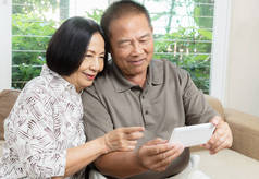 快乐的高级亚洲夫妇微笑着使用智能手机