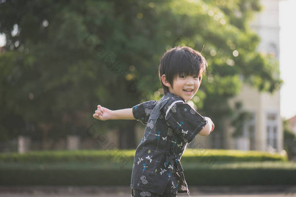 可爱的亚洲孩子在和服奔跑和<strong>回顾</strong>在公园里