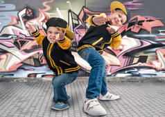 两兄弟跳舞霹雳舞。嘻哈风格。很酷的孩子。在墙上涂鸦.