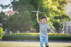 可爱的亚洲孩子，打在你身上的纸板飞机公园户外