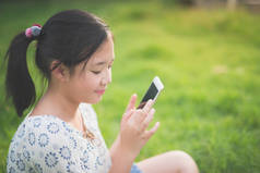美丽的亚洲女孩使用智能手机与感觉放松和笑脸, 户外