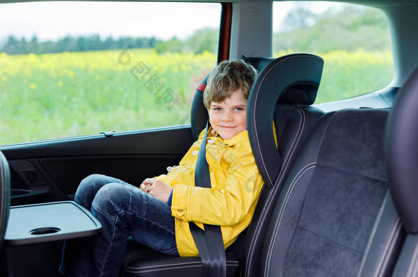 可爱可爱的学龄前孩子男孩坐在<strong>车里</strong>在黄雨外套.