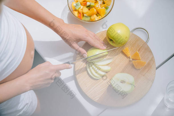 在家里用刀煮水果<strong>沙拉</strong>的孕妇裁剪照片