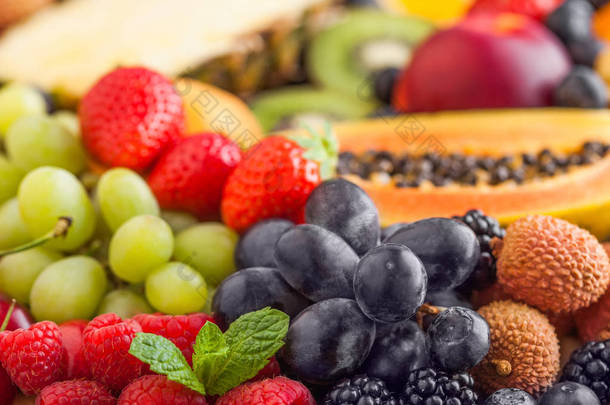 新鲜的生有机夏季浆果和异国情调的水果。宏观。闭上你的嘴菠萝、木瓜、葡萄、油桃、橘子、杏子、猕猴桃、荔枝、樱桃和植物、覆盆子.