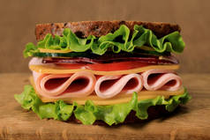 生菜、火腿、奶酪、熏肉和西红柿放在木板上的新鲜三明治