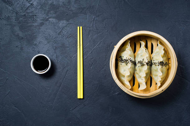 韩国饺子在传统的蒸笼里, 黄色筷子。黑暗背景, 顶部视图