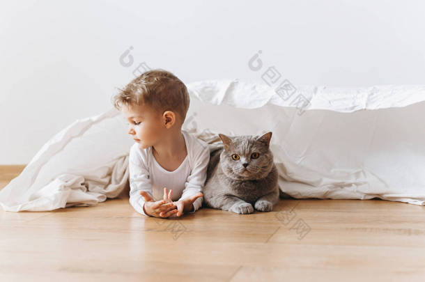 可爱的学步男孩和灰色<strong>英国</strong>短毛猫猫躺在地板上一起在家