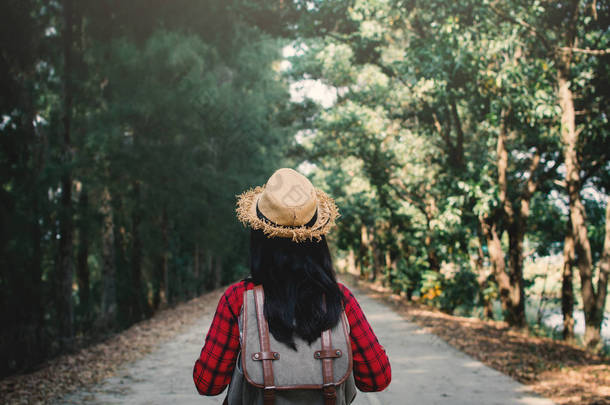 妇女背包客在道路和森林背景, 放松时间在假日概念旅行, 复古色调的颜色和柔和的焦点