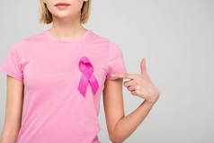 裁剪的观点, 年轻女子在粉红色的 t恤指向乳腺癌意识丝带, 隔离在灰色