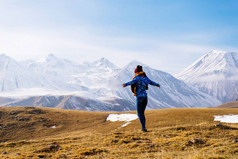 活泼的年轻女孩在蓝色夹克享受山自然和空气