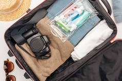 带毛巾的旅行袋,彩色瓶子的化妆品袋,数码相机,衣服的顶部视图 