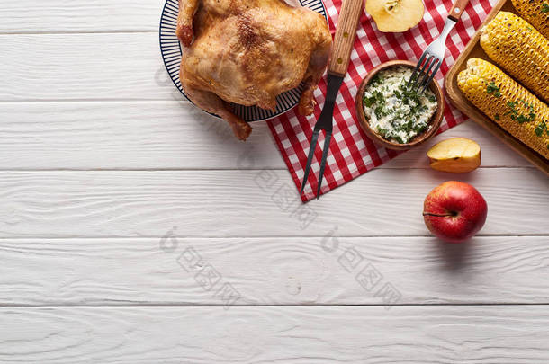 火鸡和蔬菜放在白色的木制餐桌前，配以格子布餐巾，作为感恩节大餐的上图